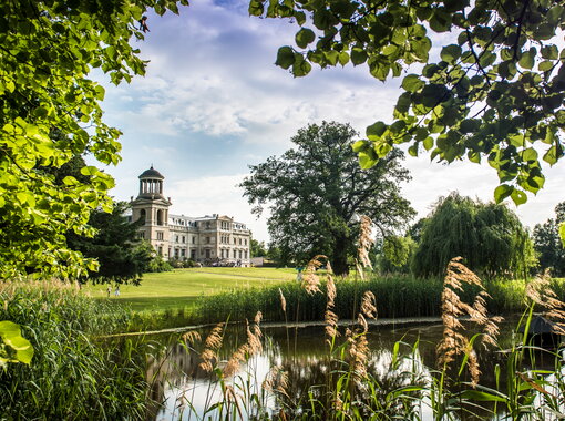 Hotel Schloss Kaarz Schlossansicht mit Blick über den Teich und durch die grüne Natur
